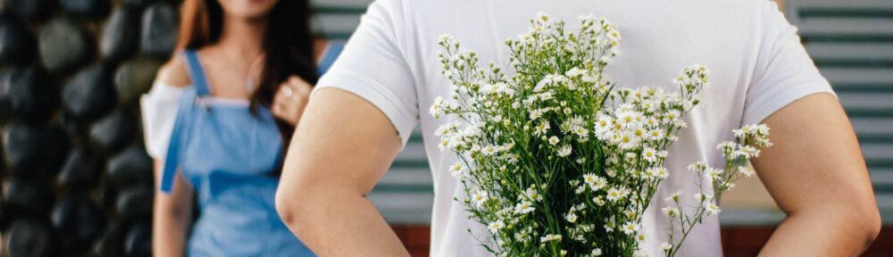 Flowers hidden behind his back. She is happy to see him.